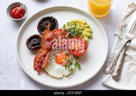 Frühstück mit Spiegelei, Tomaten, Pilzen, Speck und Avocado Stockfoto