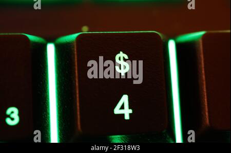 Makro Nahaufnahme von grün beleuchteten Computer-Tastatur-Taste mit Dollar zeichen und Zahl 4 (Fokus auf verschwommenes Dollarzeichen) Stockfoto