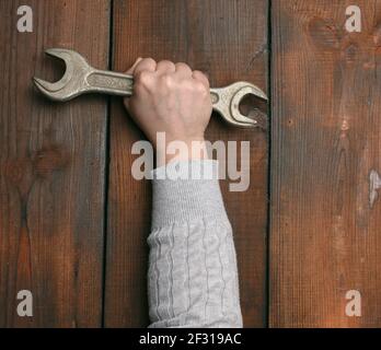 Die weibliche Hand hält einen verstellbaren Metallschlüssel für Muttern Stockfoto