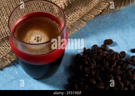 Kleines Glas auf der Seite mit Kaffeebohnen und Sacktuch. Stockfoto