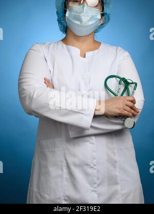 Ärztin in einem weißen medizinischen Kleid steht auf einem Blauer Hintergrund Stockfoto