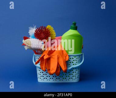 Blauer Kunststoffkorb mit Bürsten, Schwämmen und Gummihandschuhen zur Reinigung Stockfoto