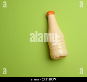 Beige Plastikflasche für Milch auf blauem Hintergrund, Behälter für flüssige Produkte Stockfoto