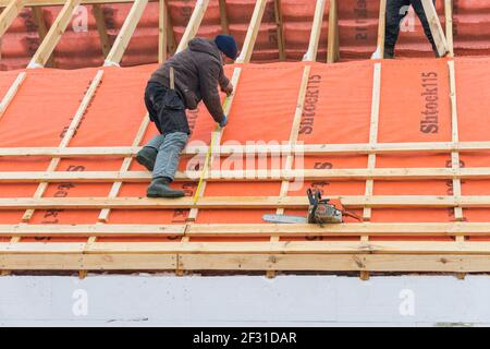 Irpin - Ukraine, März - 13, 2021: Dachdecker nimmt Messungen vor der Installation von Dachplatten und Dampfsperren für Metallfliesen im Winter ti Stockfoto