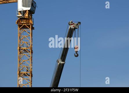 Moderne Baukräne auf blauem Himmel Hintergrund Stockfoto