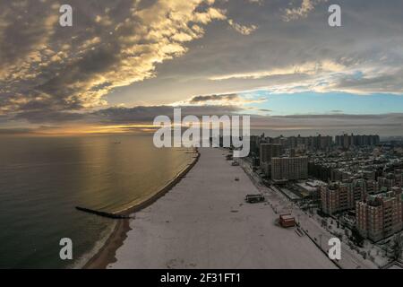 Luftaufnahme eines schneebedeckten Coney Island Beach im Winter bei Sonnenuntergang in Brooklyn, New York Stockfoto