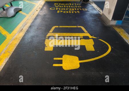 Linienmarkierungen in einer Parkbucht in gelb auf schwarzem Asphalt eines Autos und elektrischer Ladeleitung sind sichtbar. Stockfoto