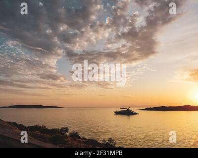 Orangefarbene Sonnenuntergangssonne über griechischen Inseln in der Ägäis bei Athen in Griechenland. Sommer Tourismus Reisen. Malerische Wolken und Yacht Segeln in ruhigen Meer Stockfoto