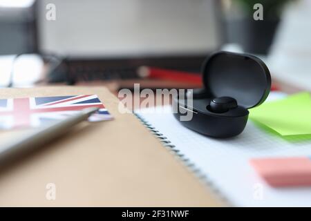 Schwarze kabellose Kopfhörer in der Box sitzen auf dem Tisch neben Notebook und Stift Stockfoto