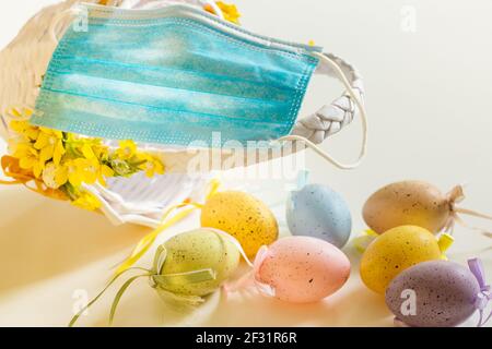 Ostereier liegen auf dem Tisch mit einer Maske zum Schutz vor Coronavirus. Das Konzept der Feiertage im Angesicht der dritten Welle des Virus Stockfoto