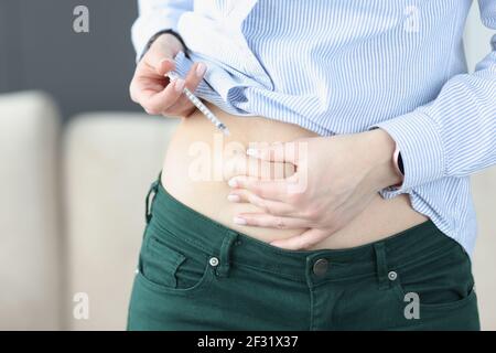 Frau injiziert sich mit Nadel und Spritze in ihren Magen Stockfoto