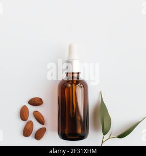 Ätherisches Mandelöl in Glasflasche mit grünem Blatt. Kosmetisches Konzept auf weißem Hintergrund, isolierte flache Lage. Hochwertige Fotos Stockfoto