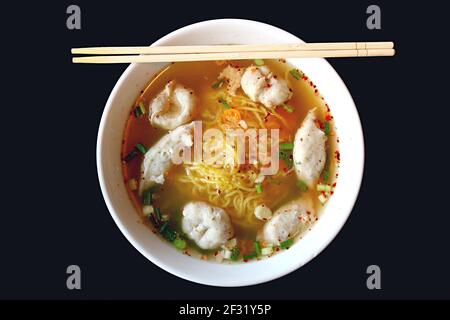 Schüssel mit köstlichen Thai Egg Noodles würzige Suppe mit sortiert Fischbälle Stockfoto