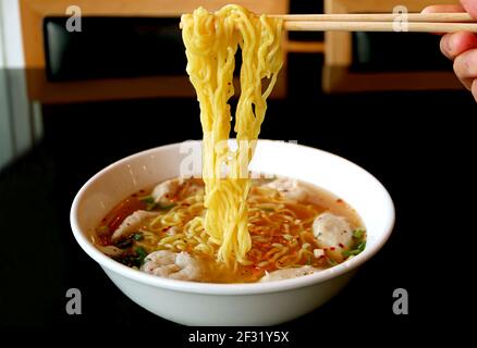 Handgreifende Thai-Eiernudeln mit verschiedenen Fischbällen Würzige Suppe Stockfoto