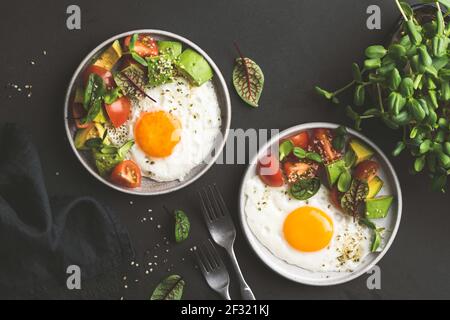 Sonniger Eierfrühstück mit Avocado-Salat auf dem Teller, Blick von oben. Gesundes Frühstück Stockfoto