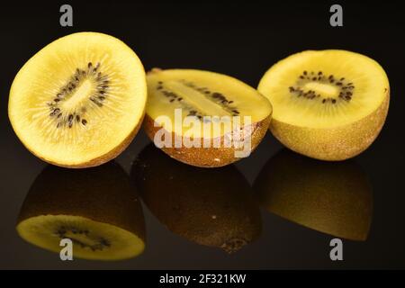 Drei Hälften von reifen Bio süß lecker goldenen Kiwi, auf schwarzem Hintergrund. Stockfoto