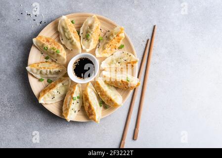 Gyoza gebratene chinesische Knödel mit Hühnerfleisch serviert mit Sojasauce auf einer Bambusplatte. Blick von oben auf asiatische Lebensmittel Gyoza Knödel Stockfoto