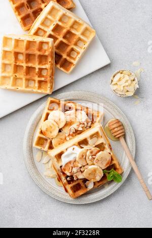 Süße belgische Waffeln mit Sahne, Banane und Hon Stockfoto