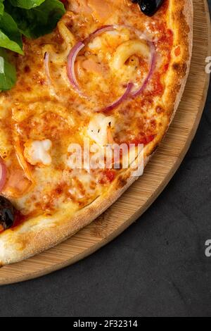 Köstliche Meeresfrüchte-Pizza auf dunkelgrauem Steintisch Stockfoto