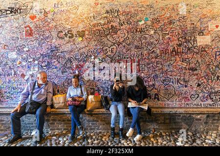 Italien, Verona, Casa di Giulietta, eine Wand von Graffiti bekennende Liebe, mit vier Personen auf einer Bank sitzen. Stockfoto