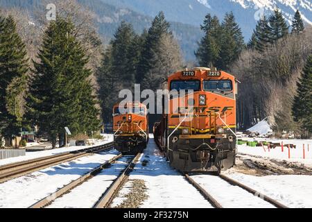 Zwei BNSF-Güterzüge in Skykomish in Washington Kaskadiert Berge, während der Winterschnee schmilzt Stockfoto