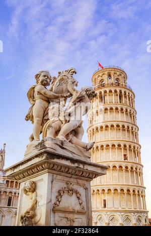 Engelsstatue auf dem Platz der Wunder in Pisa und Schiefer Turm, Italien gegen bunten Abendhimmel Stockfoto