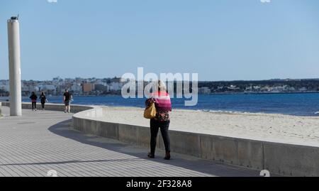 Palma, Spanien. März 2021, 14th. Eine Frau spaziert auf der Promenade des Arenal Strandes auf Mallorca. Aufgrund der geringen Inzidenz von Coronaviren ist Mallorca kein Risikogebiet mehr. Quelle: Clara Margais/dpa/Alamy Live News Stockfoto