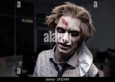 Gruseliger Geschäftsmann mit Zombie-Schmiernast im Gesicht, der dich ansieht Mit düsterem Ausdruck, während man vor der Kamera steht Büro Stockfoto