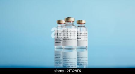 Coronavirus-Impfstoff. Drei Fläschchen mit Impfstoff auf blauem Hintergrund. Stockfoto