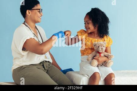 Arzt geben Faust Beule Mädchen sitzen in der Klinik. Mädchen Besuch Arzt für die Untersuchung. Stockfoto