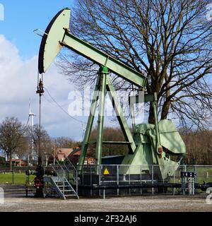 Ölbohren. Nickender Esel im Einsatz in Deutschland. Windturbinen im Hintergrund Stockfoto