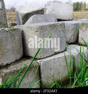 Ein Heftklammer von ungenutzten Pflastersteinen, die im Gras liegen. Stockfoto