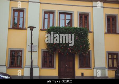 Gelbes Haus mit braunen Fenstern, Holztür, grauem Dach und Auto davor Stockfoto