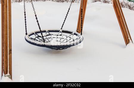 Echte leere Kinder-Runde Schaukel im Hof am Wintertag Im großen Schnee Stockfoto