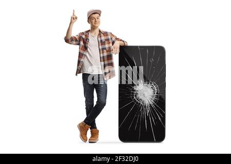 Junger Mann, der sich an ein Telefon mit einem kaputten Bildschirm lehnt Und zeigt isoliert auf weißem Hintergrund Stockfoto
