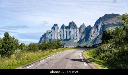 Straße, hinter felsigen Gipfel Devil's Teeth, Okshornan, Senja Island, Troms, Norwegen Stockfoto