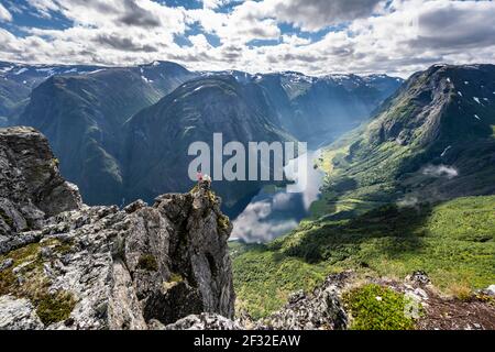 Wanderer stehen auf felsigen Ausbisse, Blick von der Spitze des Breiskrednosi, Berge und Fjord, Naeroyfjord, Aurland, Norwegen Stockfoto