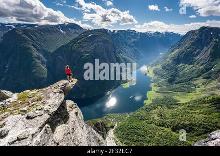 Wanderer stehen auf felsigen Ausbisse, Blick von der Spitze des Breiskrednosi, Berge und Fjord, Naeroyfjord, Aurland, Norwegen Stockfoto