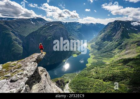 Wanderer stehen auf felsigen Ausbisse, Blick von der Spitze des Breiskrednosi, Berge und Fjord, Naeroyfjord, Aurland, Norwegen Stockfoto