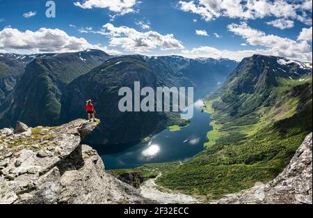 Wanderer stehen auf felsigen Ausbisse, Blick von der Spitze des Breiskrednosi, Berge und Fjord, Naeroyfjord, Aurland, Norwegen Stockfoto