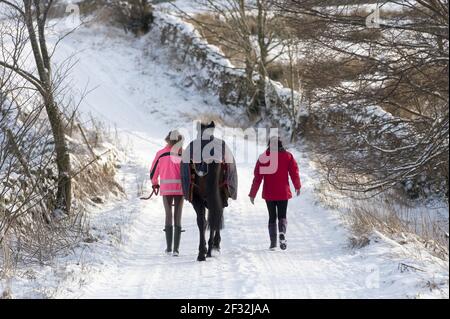 Mutter und Tochter, die am verschneiten Morgen auf der Straße reiten, Hawes, Wensleydale, Yorkshire Dales N.P., North Yorkshire, England, Vereinigtes Königreich Stockfoto