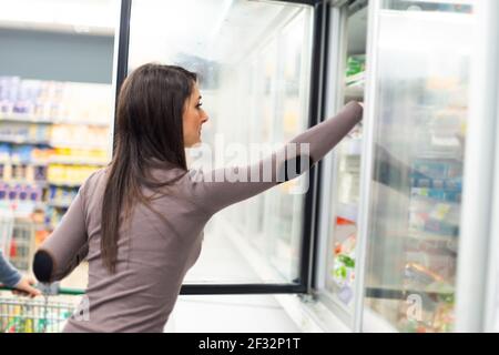 Frau, die tiefgefrorene Lebensmittel aus einem Gefrierschrank in einem Spuermarket Stockfoto