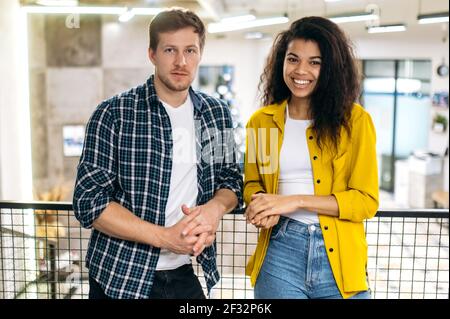 Portrait von multiethnischen Freunden Studenten oder Kollegen in stilvoller Kleidung am Arbeitsplatz. Glücklicher junger Erwachsener erfolgreicher männlicher und weiblicher Angestellter, der die Kamera anschaut, lächelt, arbeitet oder studiert zusammen Stockfoto