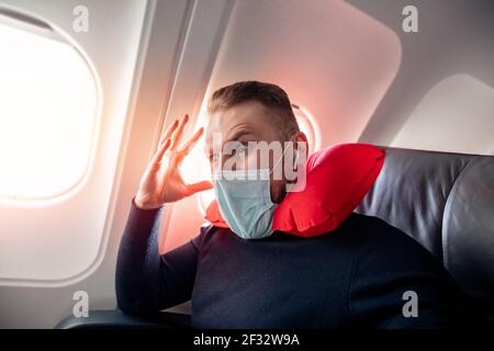 Konzept Aerophobie oder Aviophobie. Angst vor Angst fliegen im Flugzeug und Höhe Tourist Mann in sichere medizinische Maske. Stockfoto