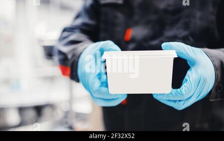 Werksingenieur hält fertiges Produkt in weißem Kasten mit Platz für Logo, Kopierraum. Stockfoto