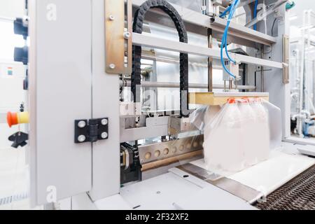 Milchfabrik Industrie, automatische Verpackung von Flaschen mit Milch in Plastiktüten. Stockfoto