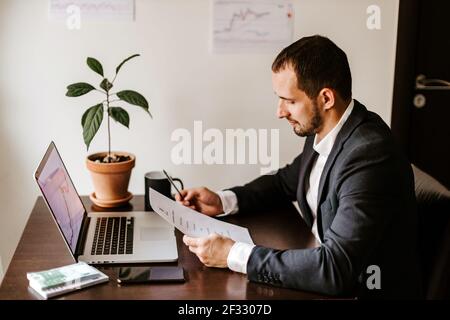 Konzentrierter junger Geschäftsmann, der im Büro am Laptop arbeitet Stockfoto