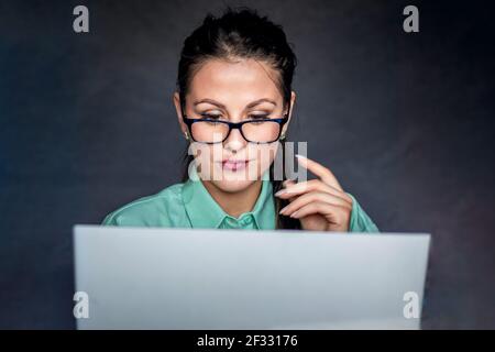 Junge Geschäftsfrau mit einem Videoanruf. Isoliert auf dunklem Hintergrund Stockfoto