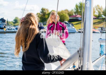 Vor dem Wettkampf auf Segelbooten zwei niedliche Mädchen Athleten Rüsten Sie ihre Segelyacht aus Stockfoto