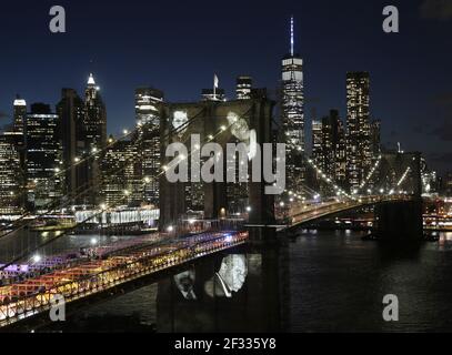 New York, USA. März 2021, 14th. New Yorker, die aufgrund von COVID ihr Leben verloren haben, lassen ihre Bilder auf die Brooklyn Bridge projizieren, als Bürgermeister Bill de Blasio "A COVID-19 Day of Remembrance" veranstaltet, eine offizielle Gedenkfeier zu Ehren der mehr als 30.000 New Yorker, die während der Coronavirus-Pandemie in New York verloren gegangen sind Stadt am Sonntag, 14. März 2021. Hunderte von New Yorkern, die durch COVID ihr Leben verloren haben, haben ihre Bilder Sonntagabend auf die Brooklyn Bridge projiziert, als Teil des virtuellen Denkmals der Stadt, das die Erinnerung an die lokalen COVID-19-Opfer ehrt. Kredit: UPI/Alamy Live Nachrichten Stockfoto